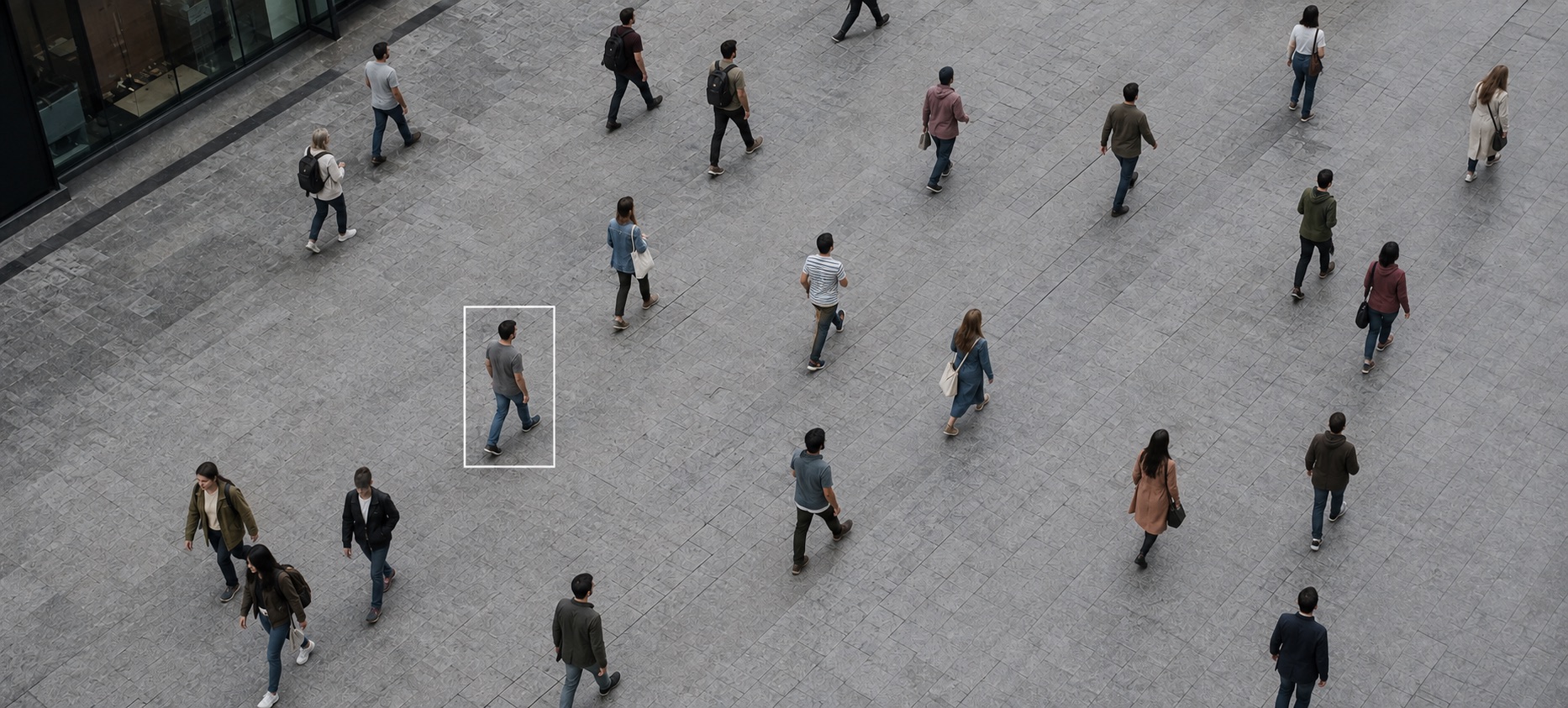 Overhead camera view of a busy plaza, with one walking figure enclosed in a detection box.
