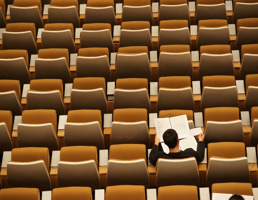 Tiered auditorium seating, with one person working alone in a row.