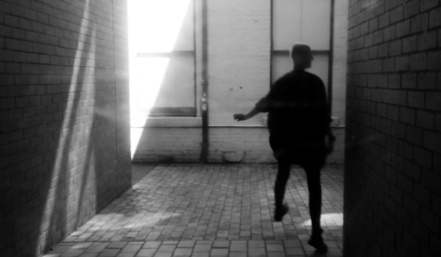 A figure walking down a lit corridor.