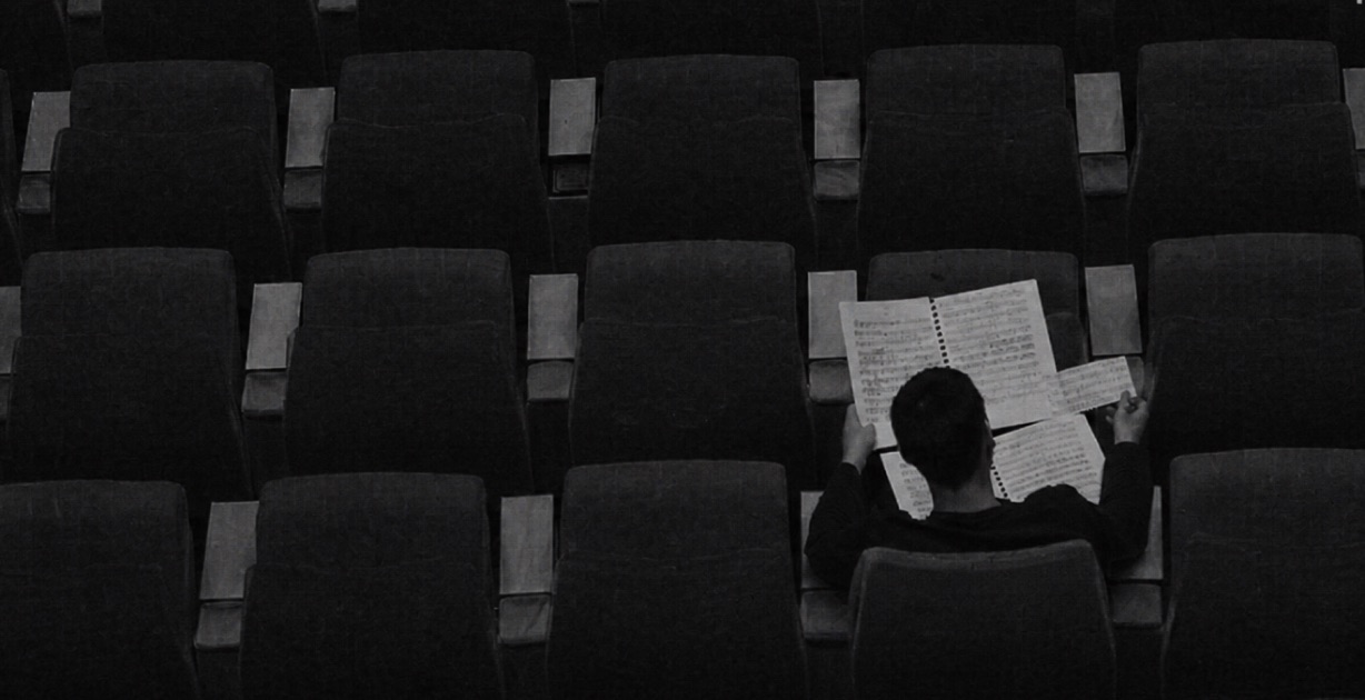 Rows of empty seating in a darkened auditorium with one item left behind.